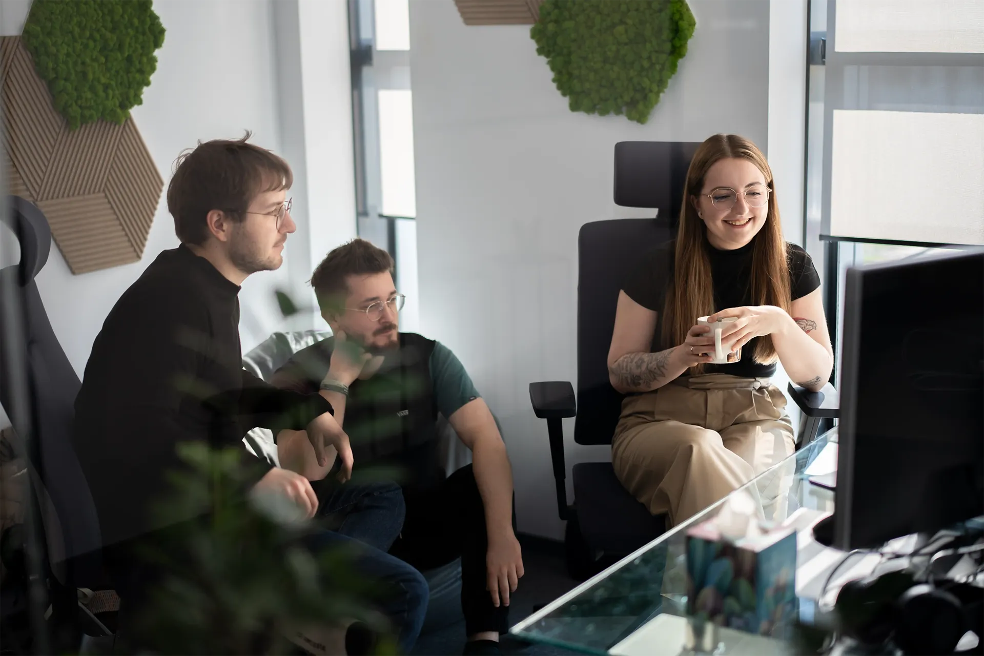 Three people sit and talk in a modern office.